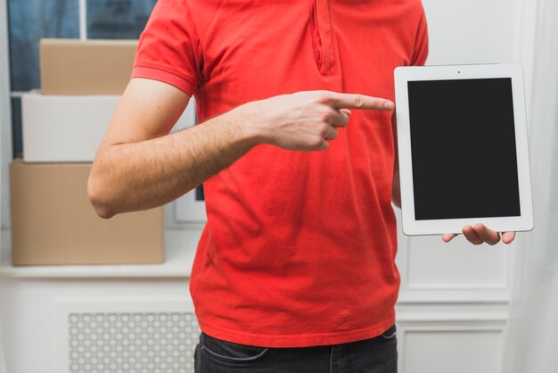 Crop courier pointing at tablet