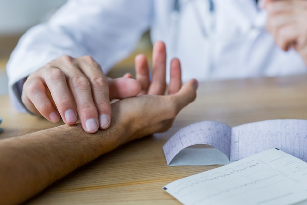 Foto gratuita ritaglia il medico che controlla l'impulso del paziente