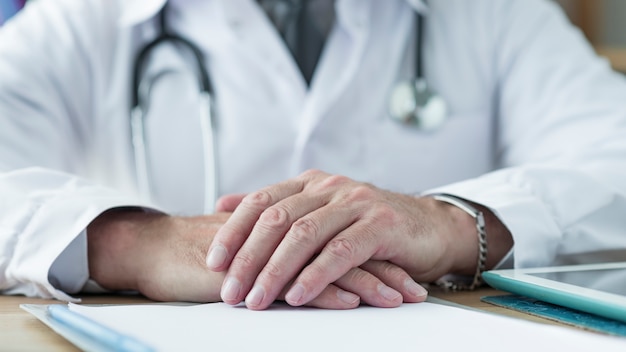 Free photo crop doctor holding hands on desk