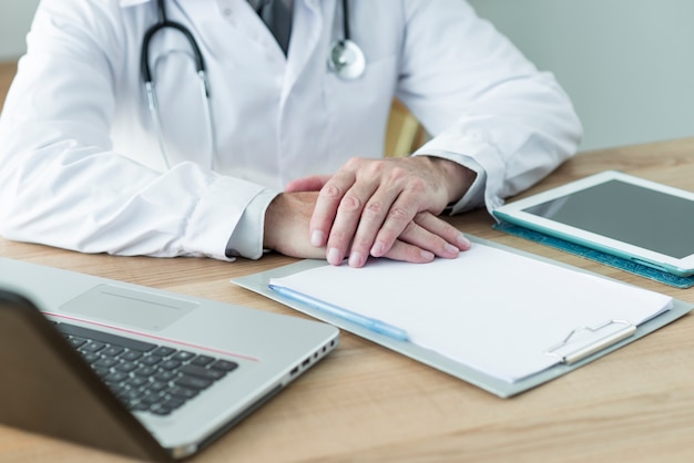 Free photo crop doctor sitting near devices in office