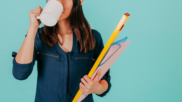 Crop draftswoman drinking hot beverage