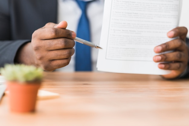 Crop ethnic man showing papers