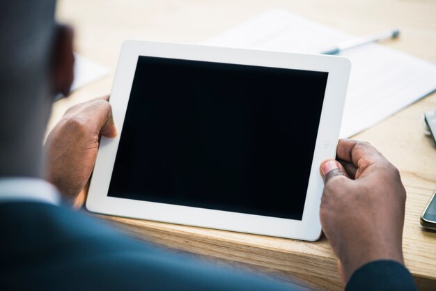 Crop ethnic man in suit with tablet