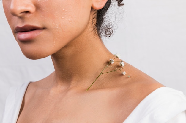 Crop ethnic woman with plant on neck