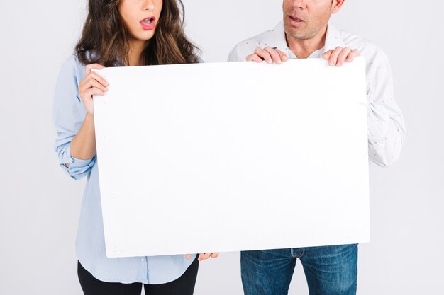 Crop father and daughter holding blank poster