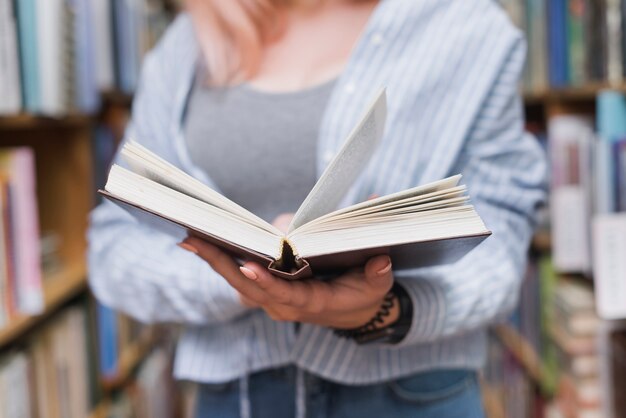 Crop female teenager reading book