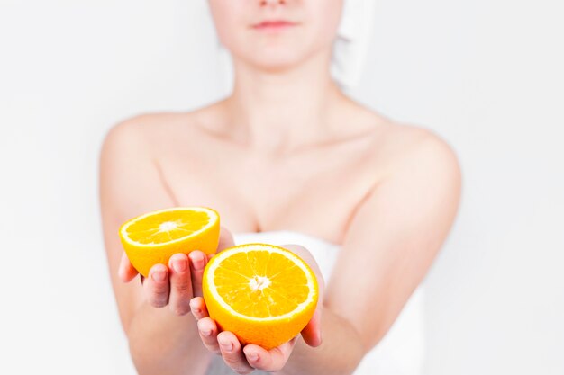 Crop female in towel holding orange slices