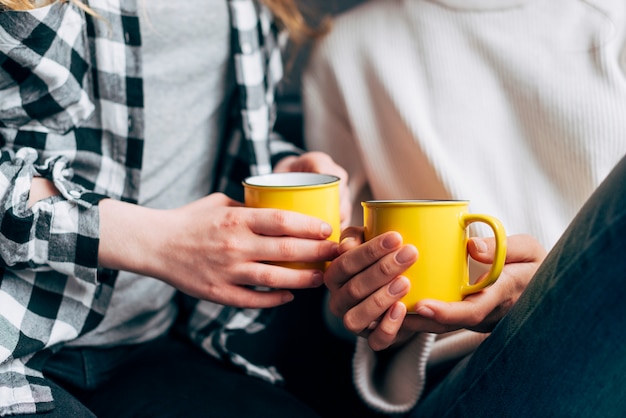 Crop females holding yellow mugs