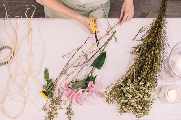 Crop florist cutting flowers for bouquet