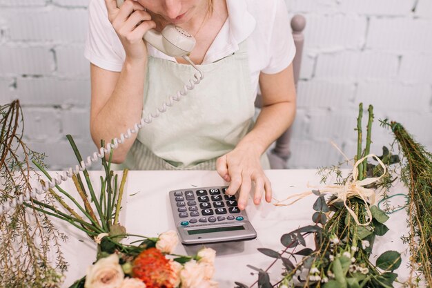 Crop florist using calculator during phone conversation