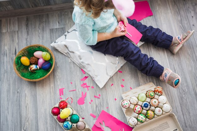 Crop girl cutting paper near eggs