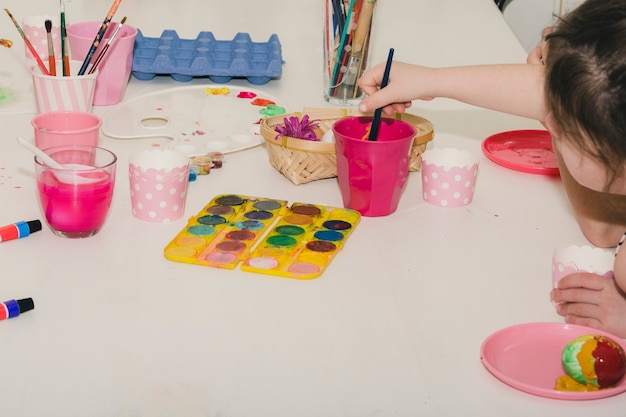 Crop girl painting eggs