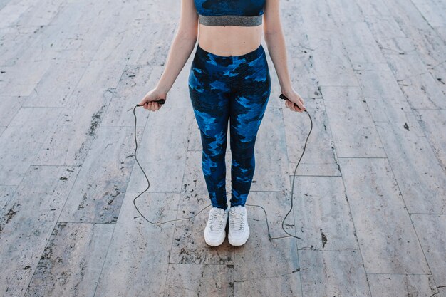 Crop girl in sportswear with jumping rope