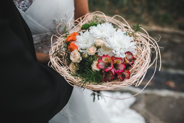 Бесплатное фото Урожай жениха, обнимающего невесту с букетом