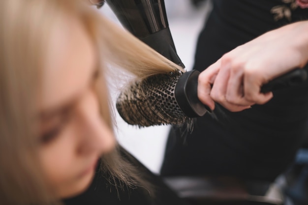 Crop hairstylist setting hair with brush