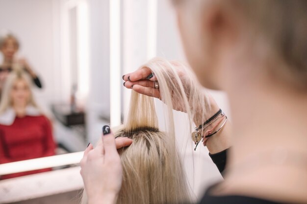 Crop hairstylist working with young client