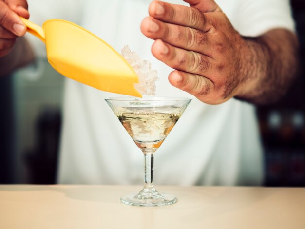 Crop hand adding ice in glass