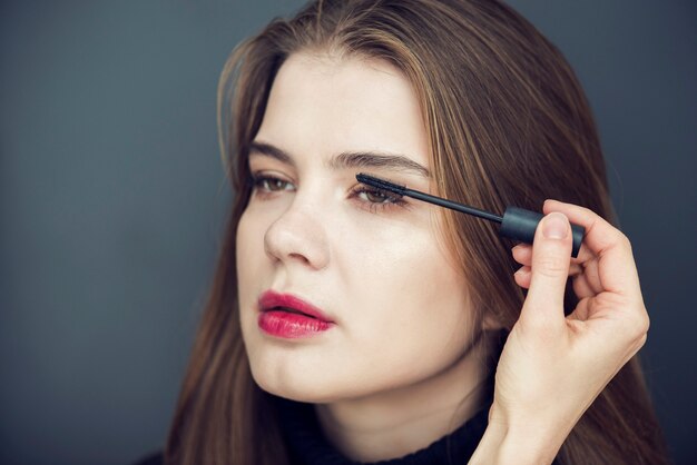 Crop hand applying mascara on model