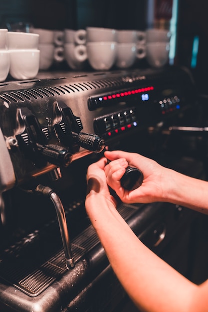 Crop hand attaching portafilter to coffee machine
