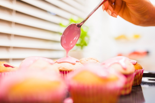 Crop hand decorating muffins