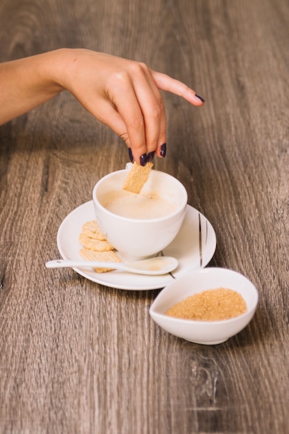 Free photo crop hand dunking cookie into coffee