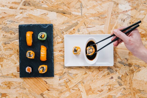 Crop hand dunking sushi into soy sauce