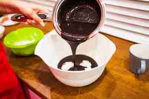 Free photo crop hand filling bowl with chocolate sauce