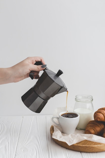 Crop hand filling cup with coffee