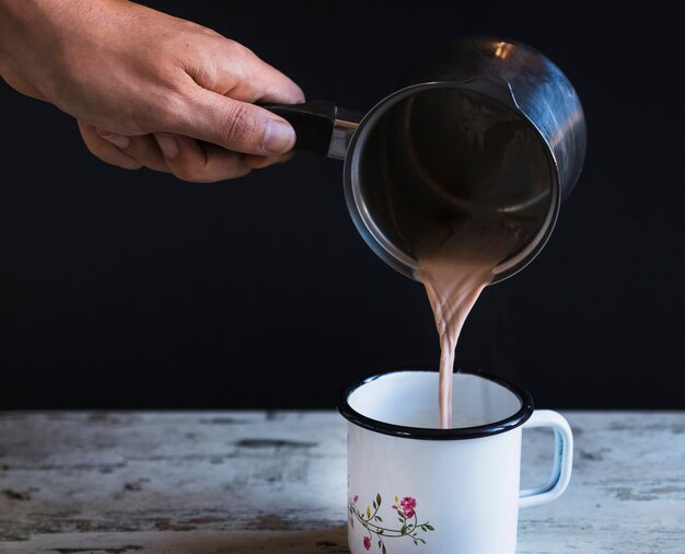 핫 초콜릿으로 손을 채우는 컵을 자르십시오