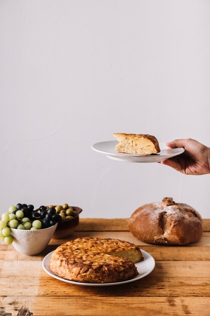 Crop hand holding cake near food