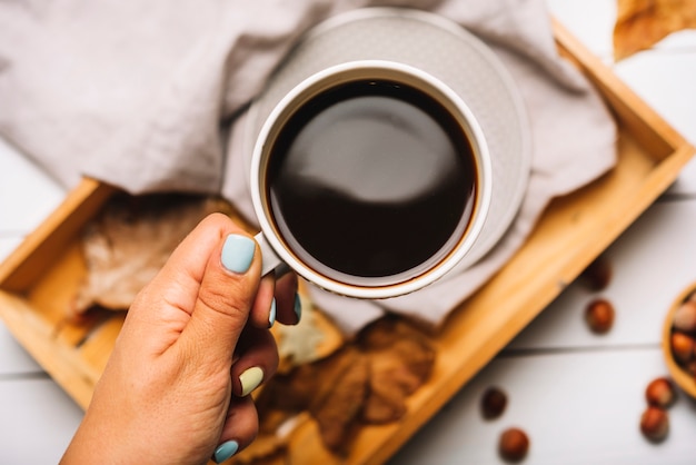 Crop hand holding coffee over tray