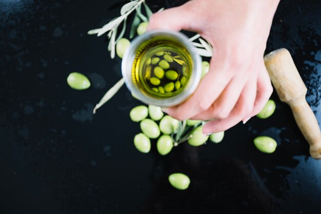 Crop hand holding glass of olive oil