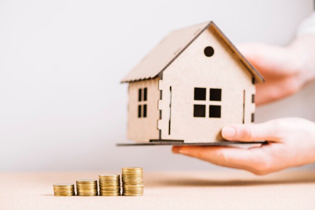 Crop hand holding house near coins