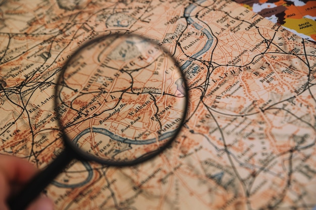 Crop hand holding magnifying glass over map