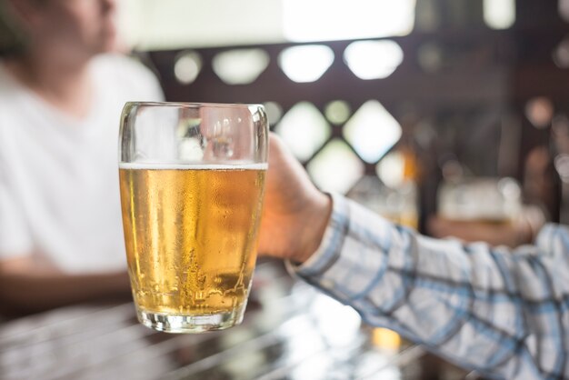 Crop hand holding mug of cold beer