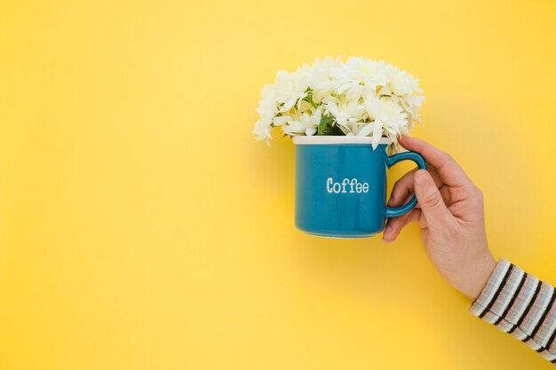 Crop hand holding mug with flowers