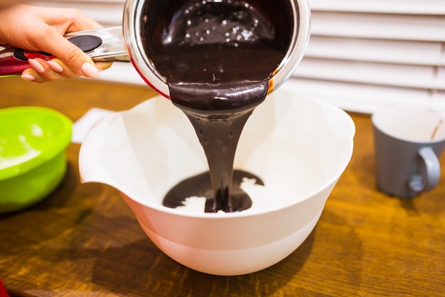 Crop hand pouring chocolate sauce into bowl