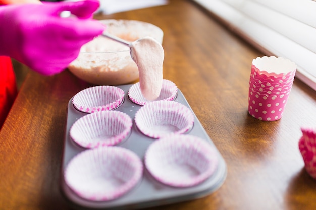 Crop hand putting batter in paper cups