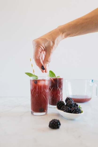 Crop hand putting blueberry into glass