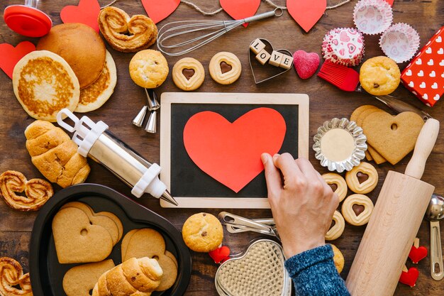 Crop hand putting heart on blackboard