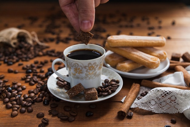 Crop hand putting sugar into coffee