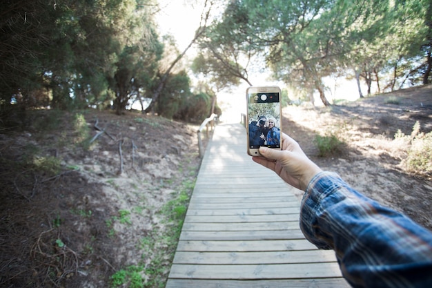 Foto gratuita ritaglia la mano che prende selfie sul percorso di legno