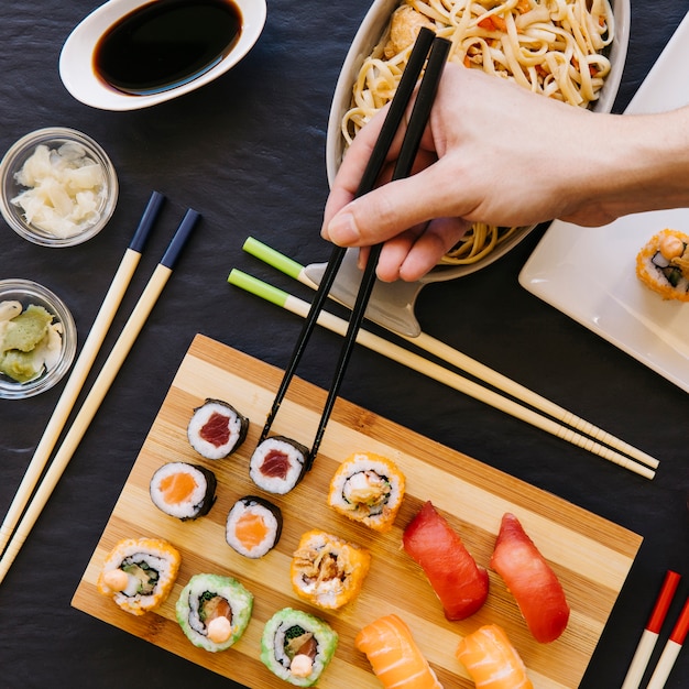 Crop hand taking sushi from board