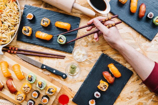 Crop hand taking sushi from board