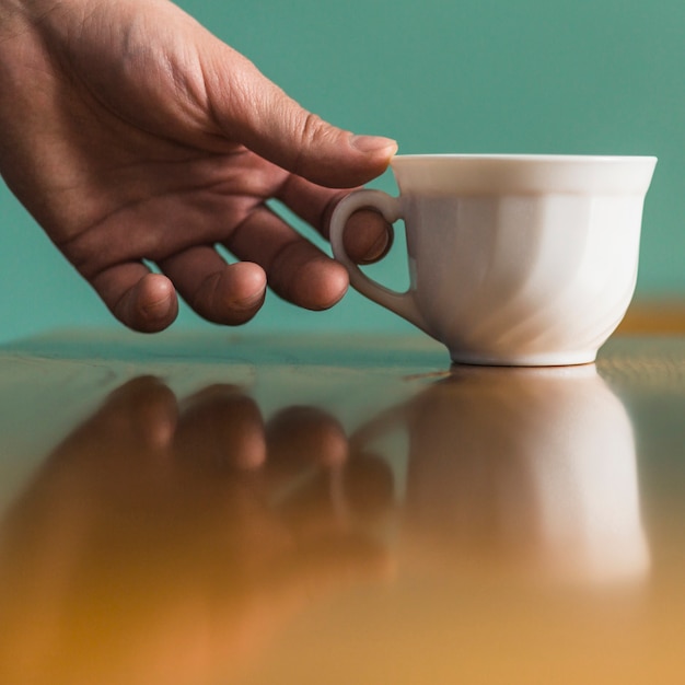 Crop hand taking white porcelain cup