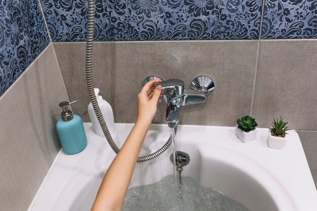 Crop hand touching bath tap