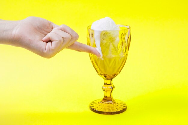 Crop hand touching melting ice-cream on cup