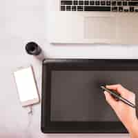 無料写真 スマートフォンやノートパソコンの近くでグラフィックタブレットを使用して手作業