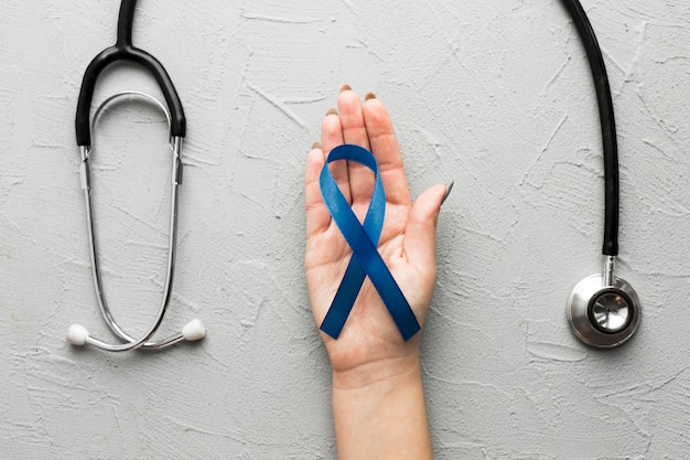 Free photo crop hand with blue ribbon near stethoscope