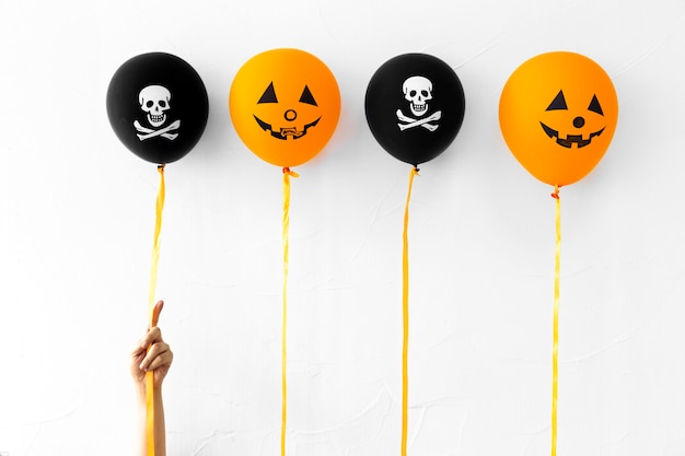 Crop hand with cute Halloween balloons